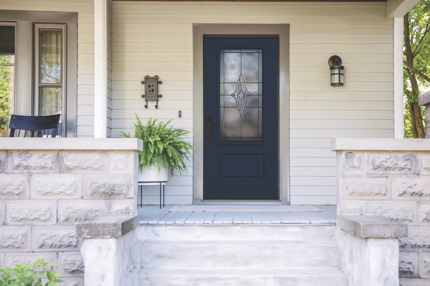 A front porch with a dark blue energy-efficient door contrasted by light-colored siding