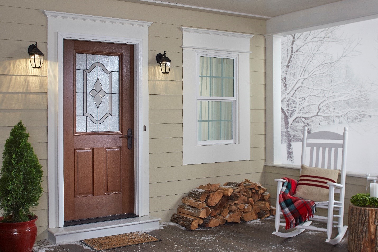 A front porch with a rocking chair, a stack of wood, and snow in the background