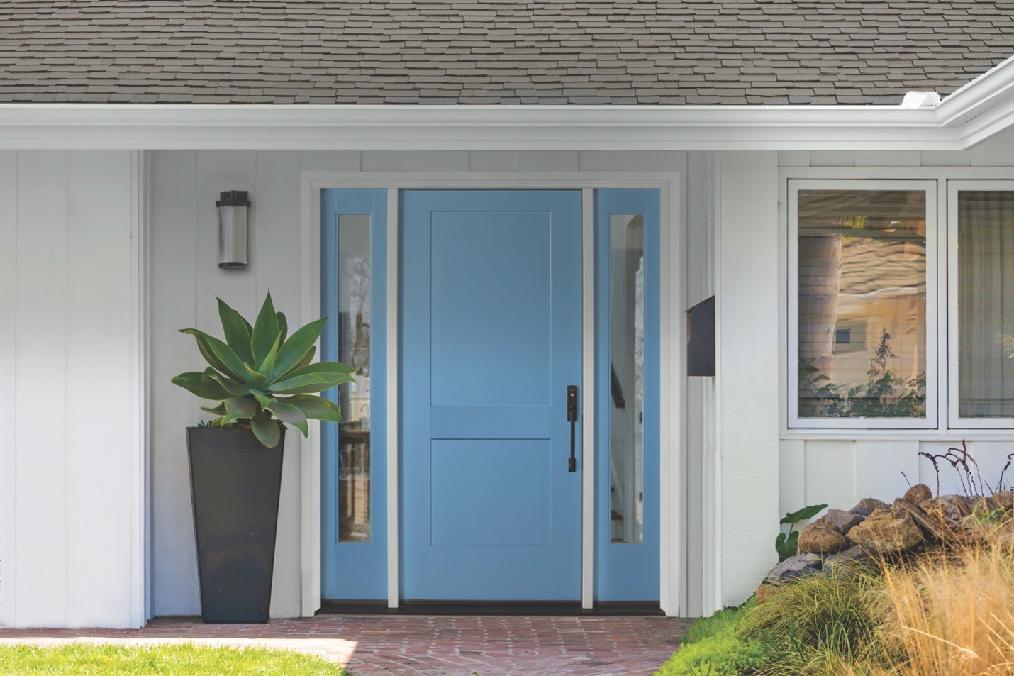 A light blue energy-efficient exterior door flanked by sidelites on a white house