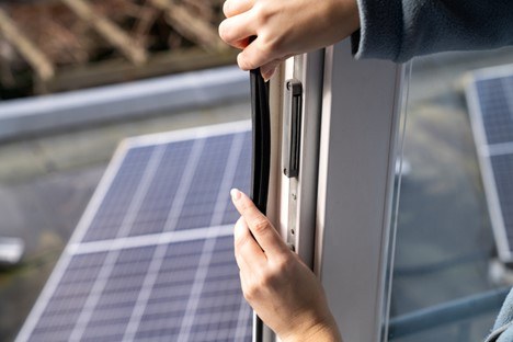 A person replacing the weather stripping on a sliding patio door to make it more energy efficient