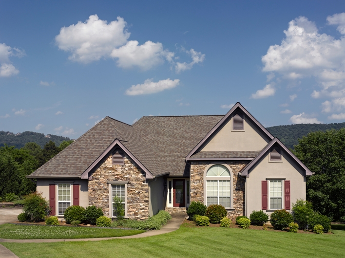 A beautiful house with stacked stone details, architectural-shaped windows, and a pristine gabled roof.