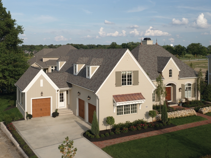 A house with curb appeal defined by its different types of roof materials and manicured lawn