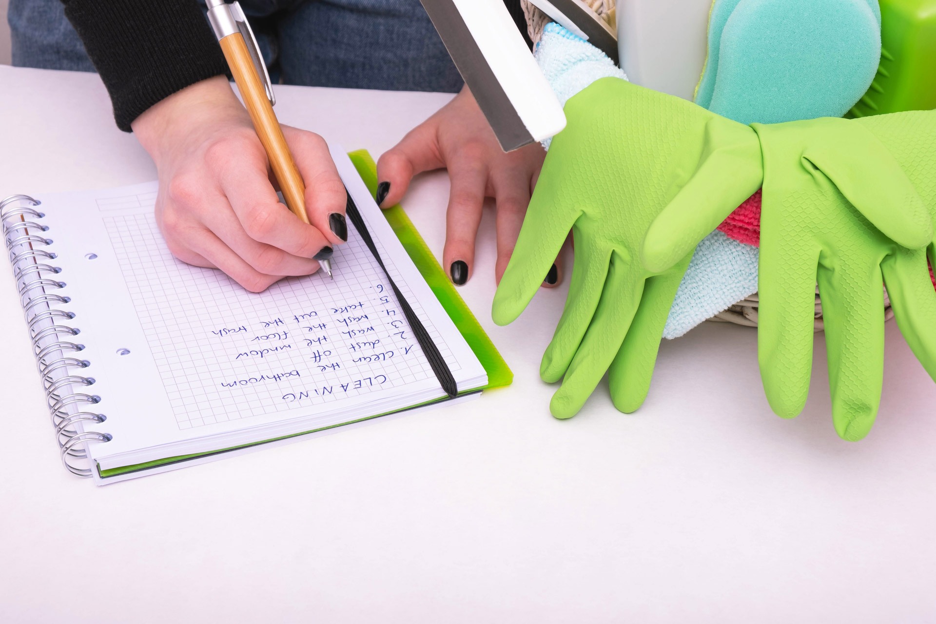 Person creating cleaning checklist in a notebook