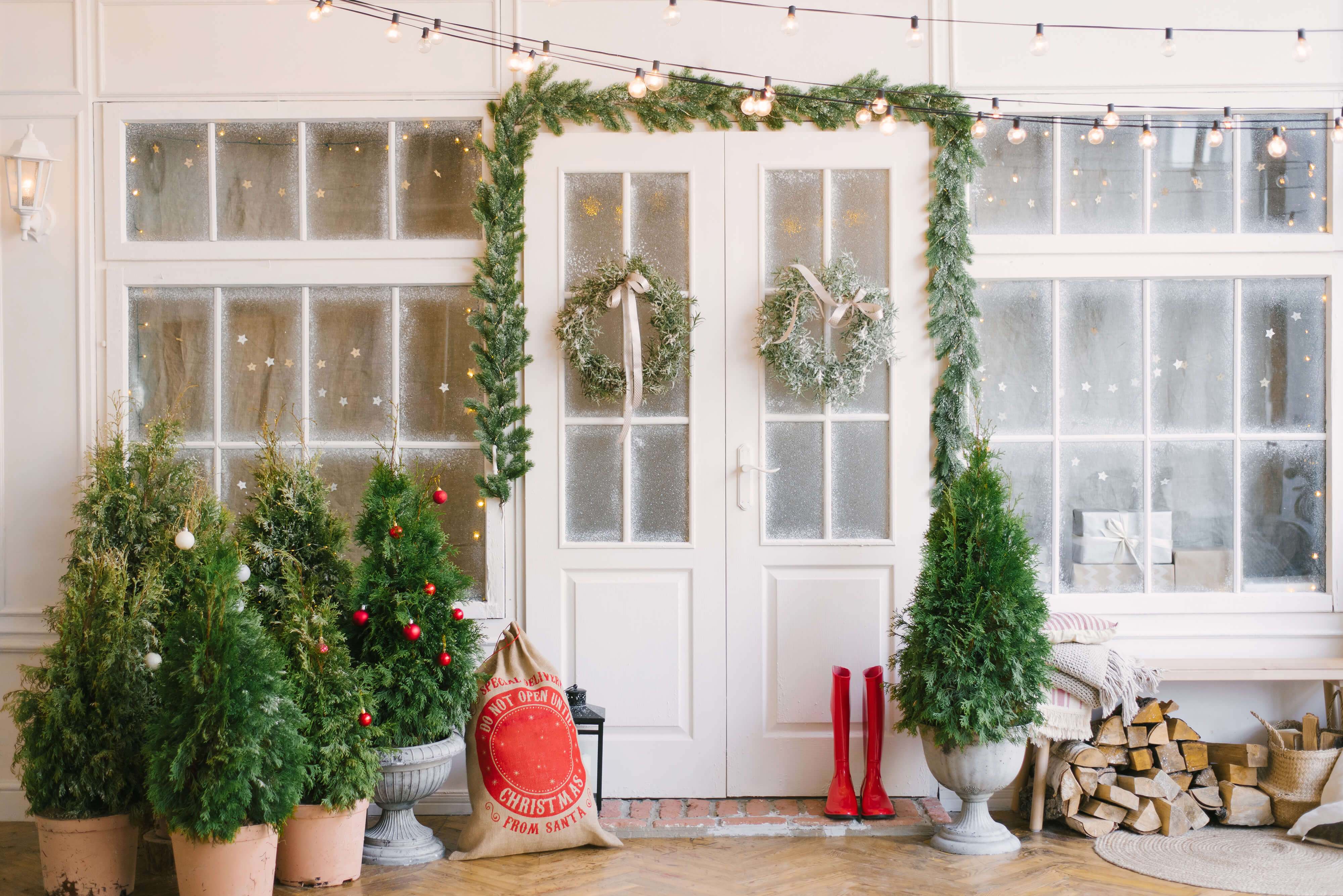 White French entry doors and windows decorated with pine garland, lights, and trees White French entry doors and windows decorated with pine garland, lights, and trees