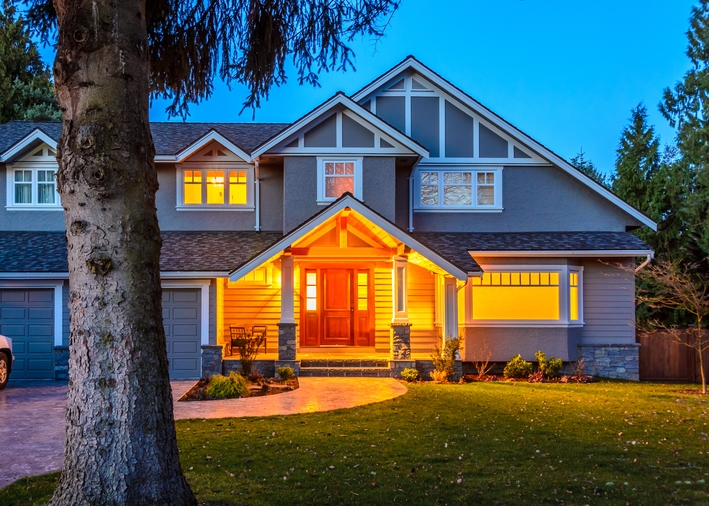 An exterior view of a house with a bright porch light and white windows