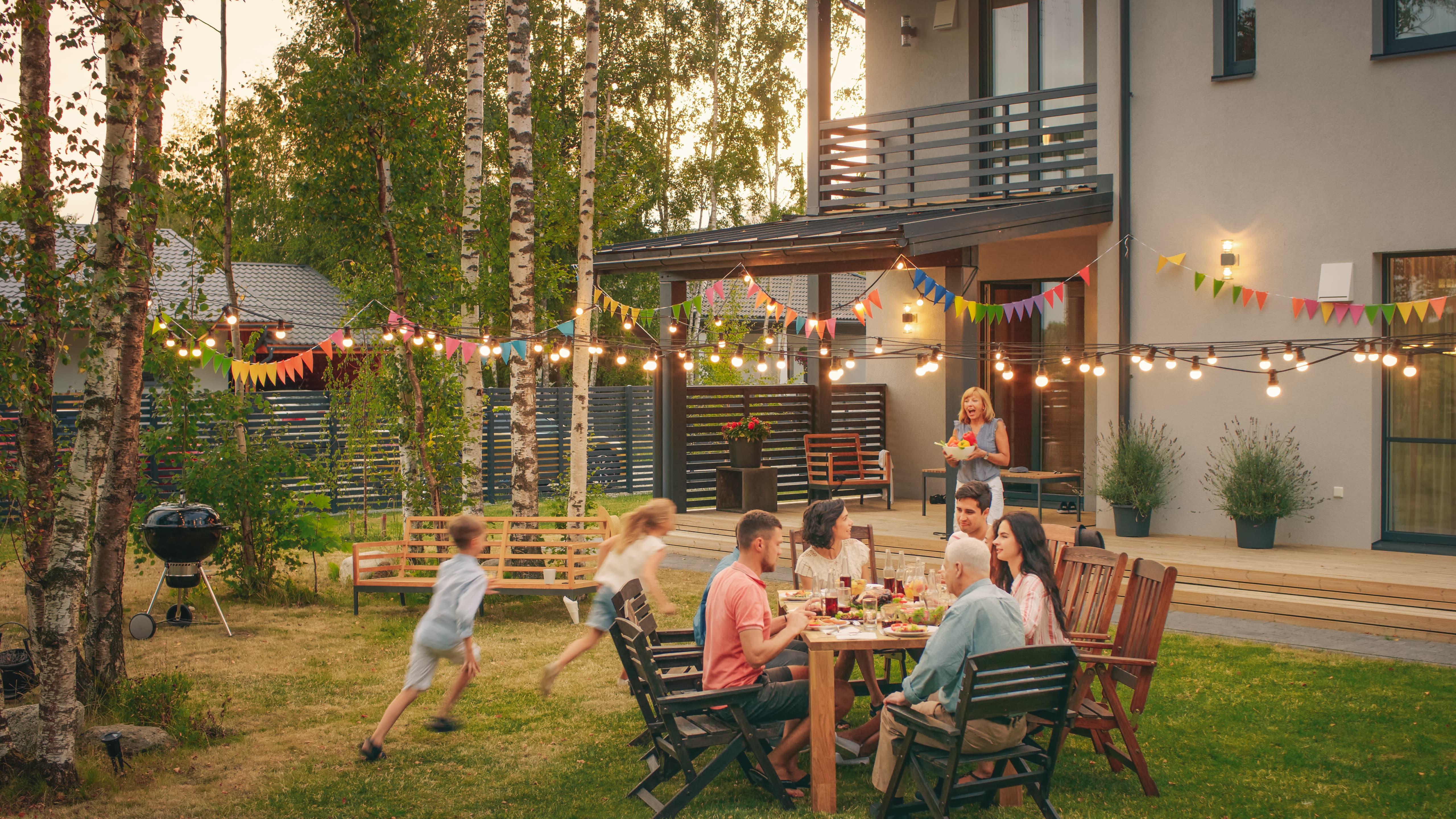 Children playing in backyard as parents sit at a table conversing