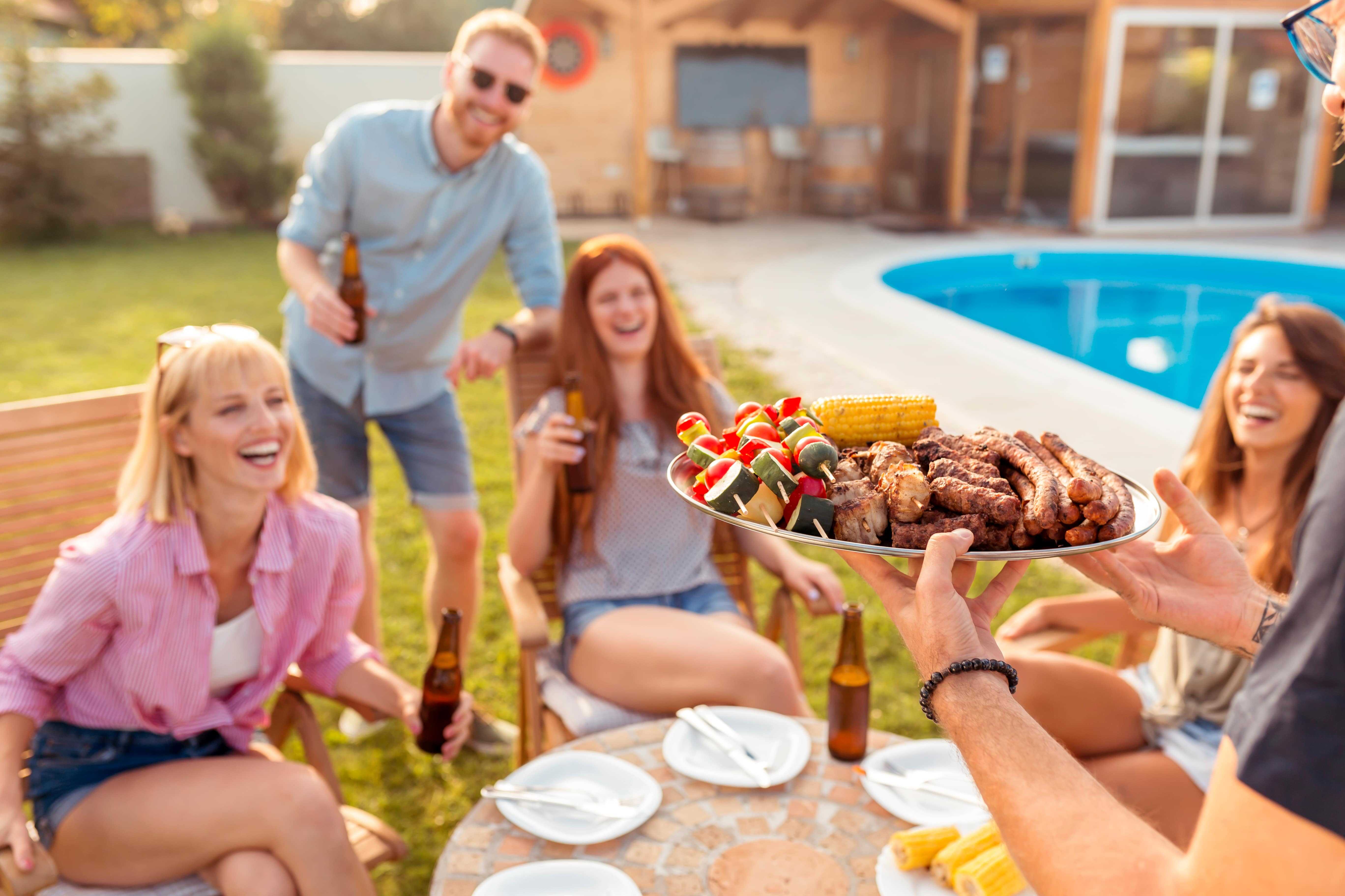 A family enjoying a backyard BBQ next to their pool