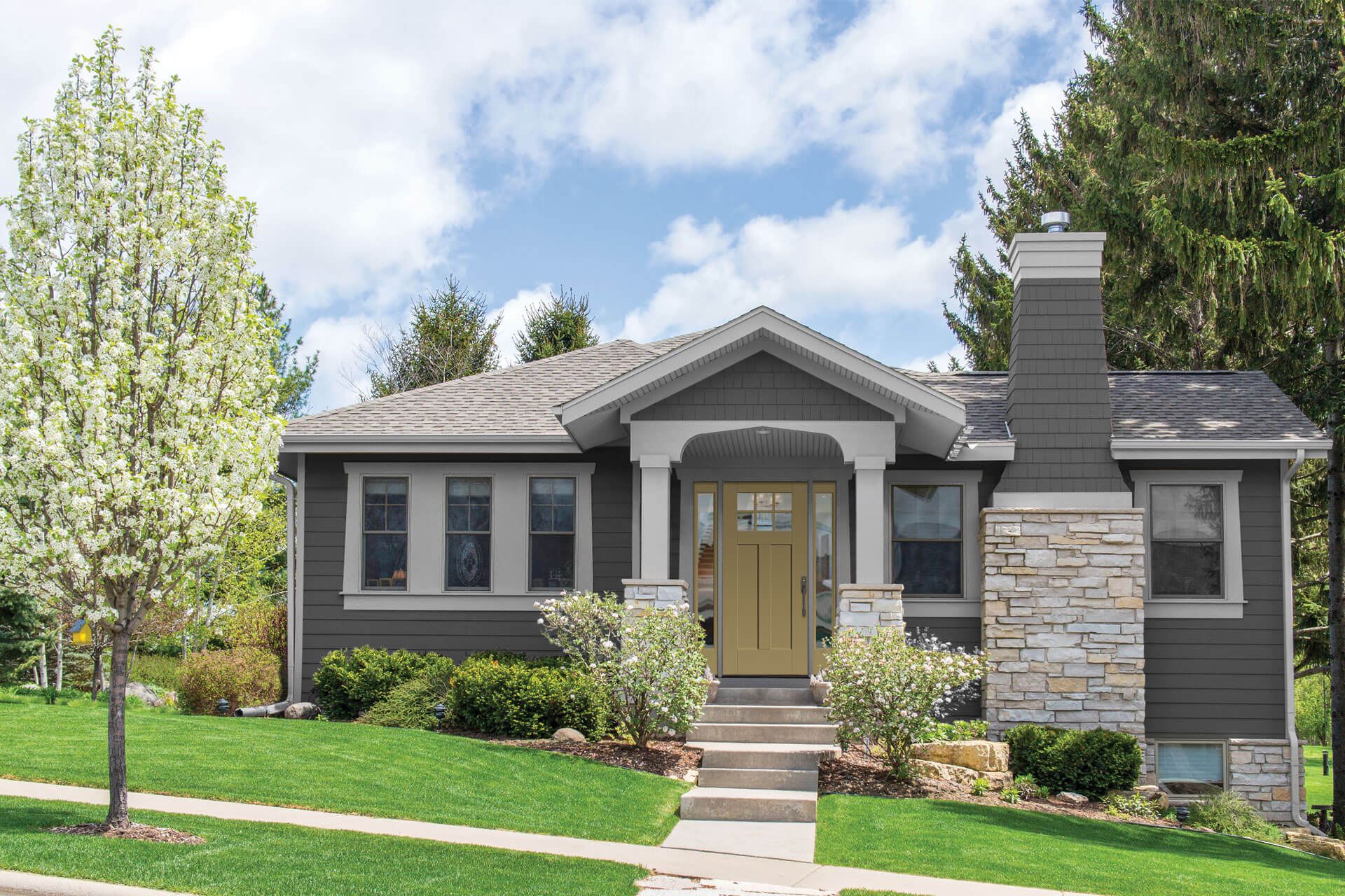 A gray house with bushes around the front door for landscaping