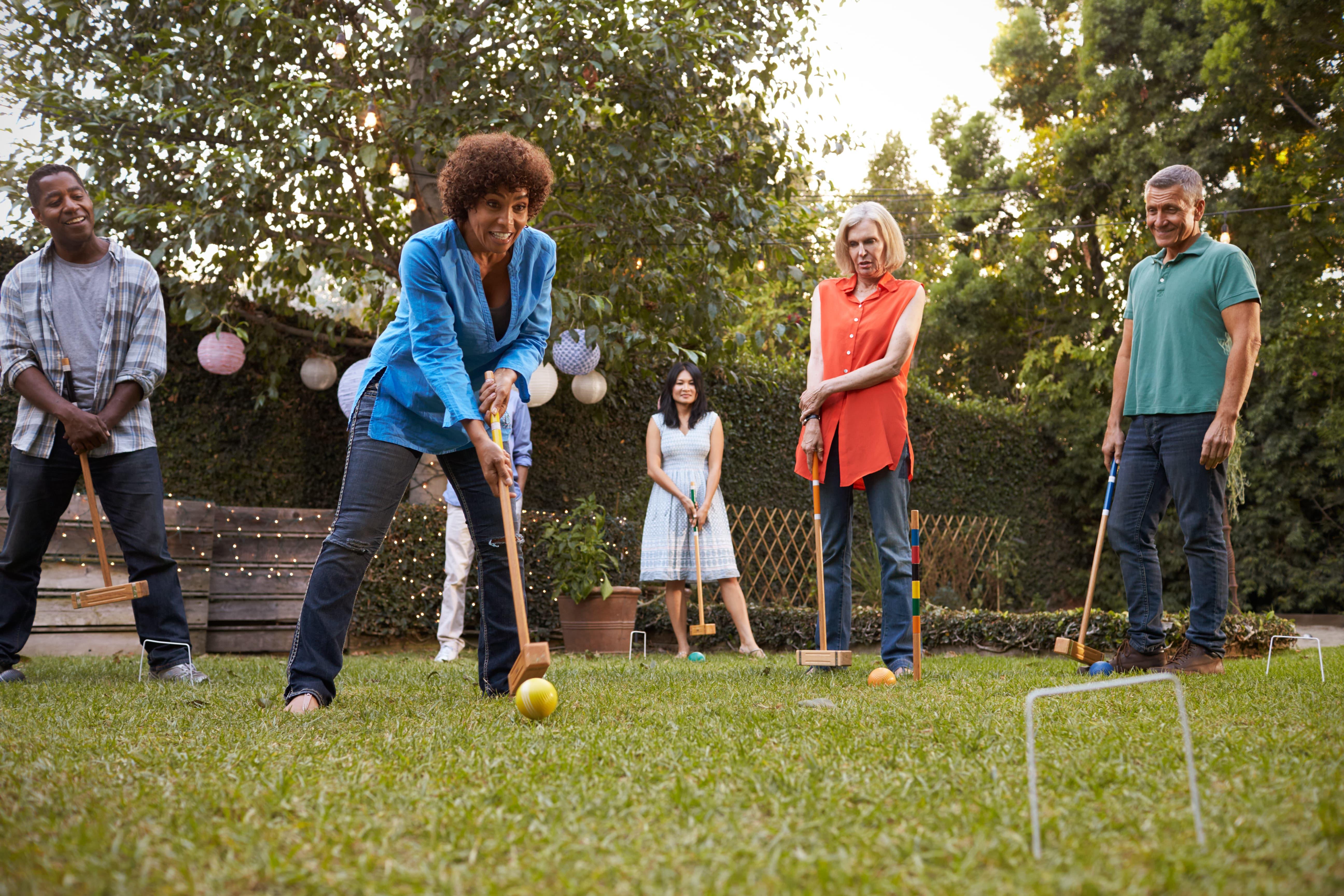 Adults playing croquet in their backyard