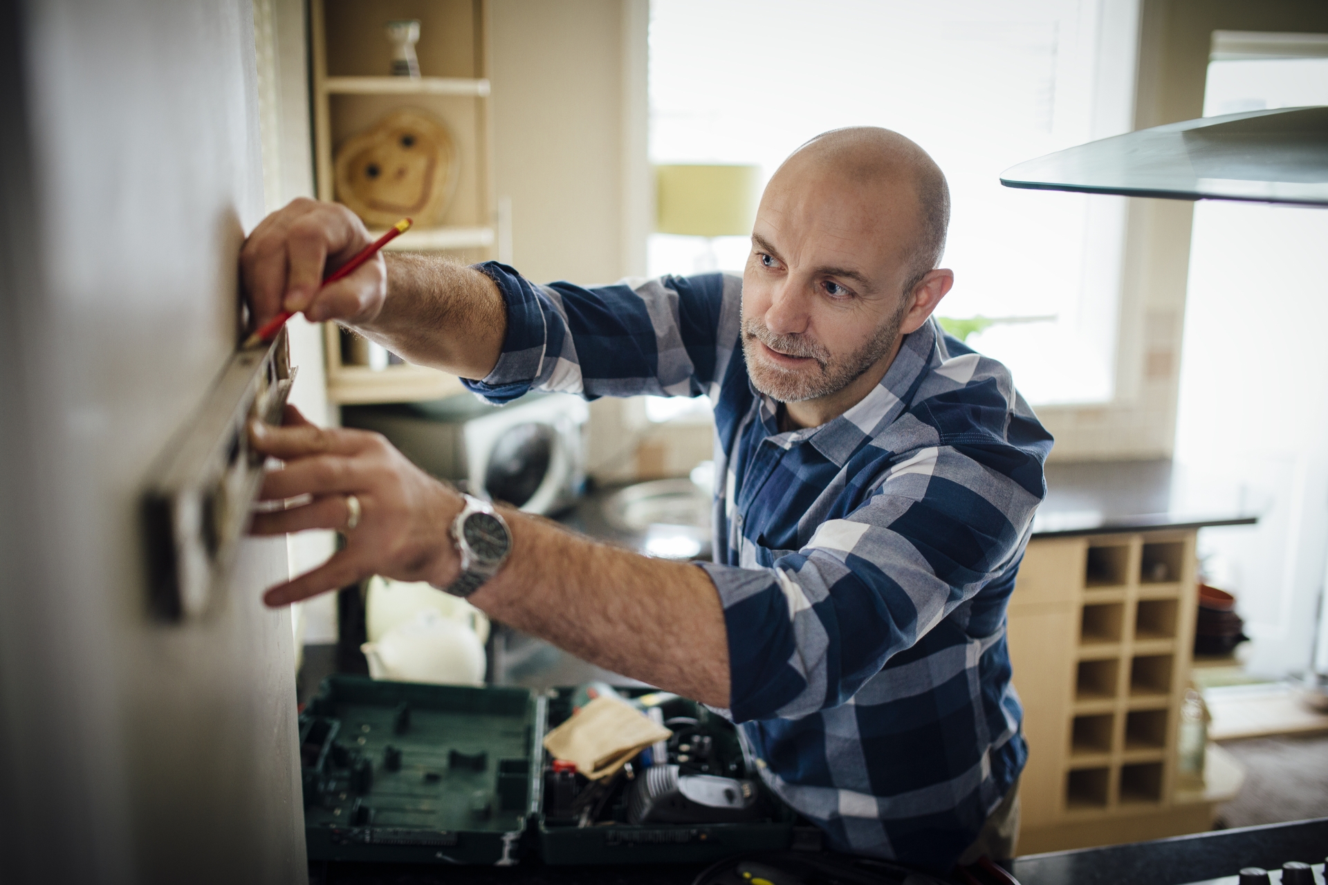 Header Stock Photo Mature Man Using A Spirit Level And Marking The Wall With A Pencil In His Kitchen