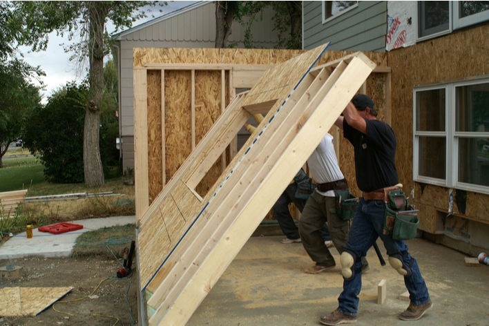 Men working to raise a wall for a new room Men working to raise a wall for a new room