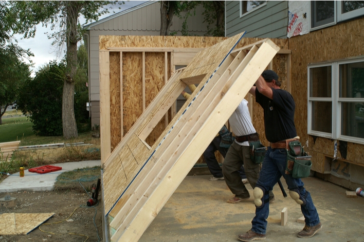 Men working to raise a wall for a new room