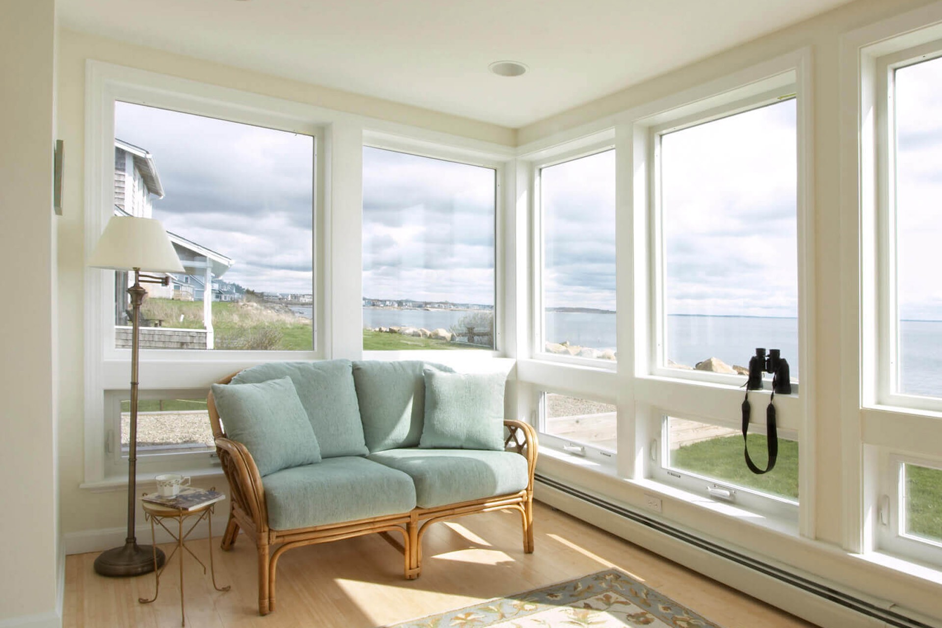 A sitting area in a beachfront home with floor-to-ceiling windows that a homeowner will need to prepare for hurricane season