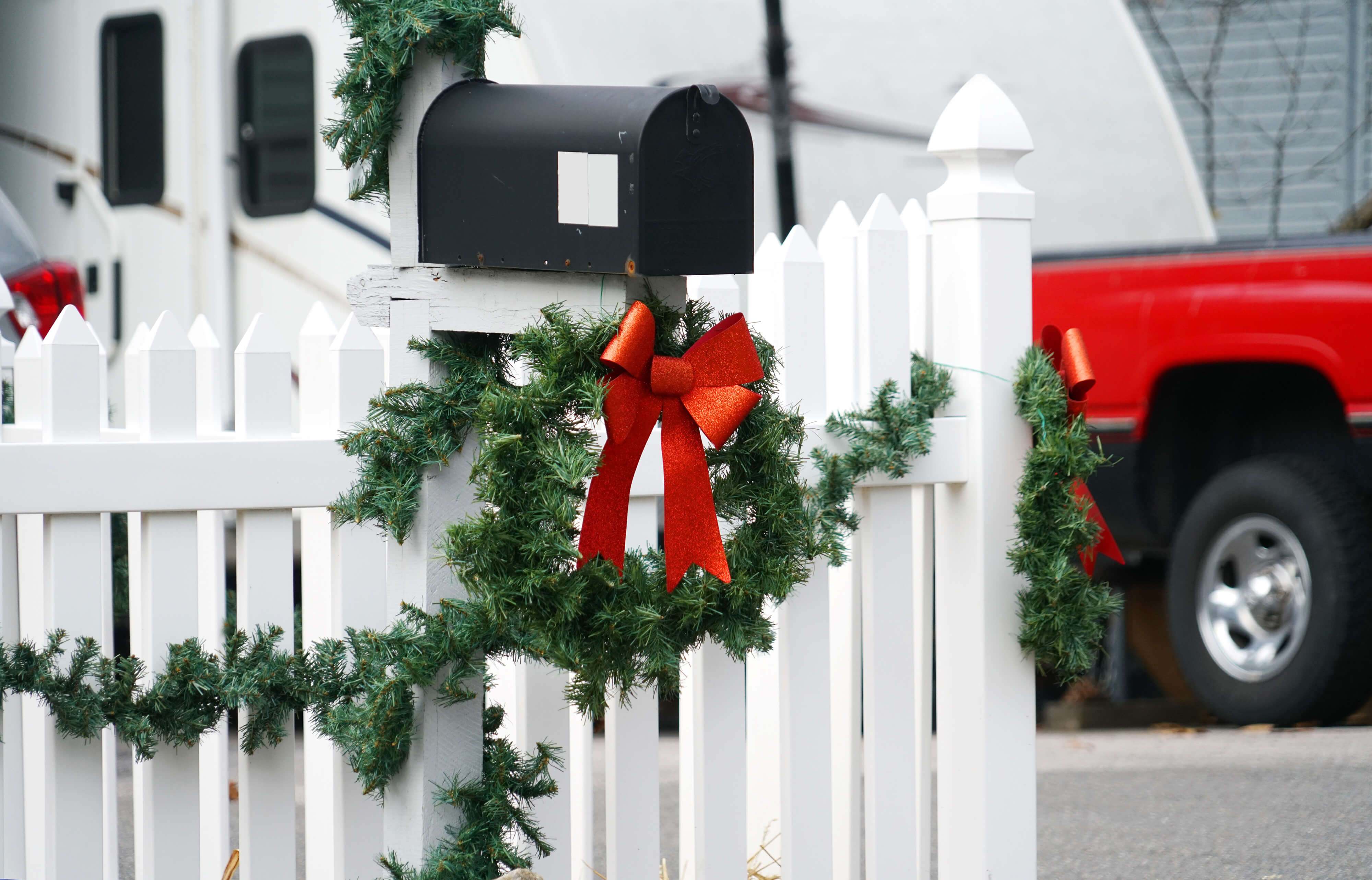White picket fence and mailbox decorated with wreath and bow White picket fence and mailbox decorated with wreath and bow