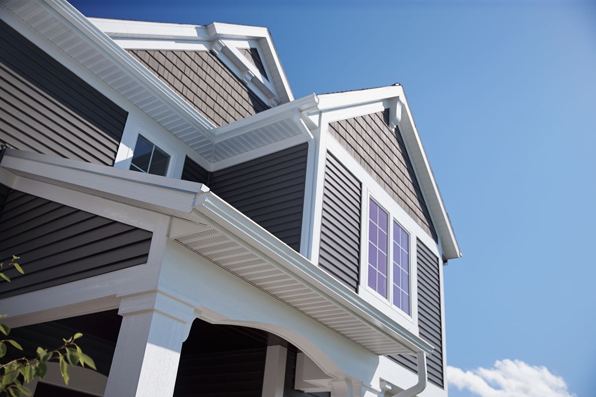 Angled perspective of a gray house with exemplary vinyl siding maintenance and gleaming white trim.