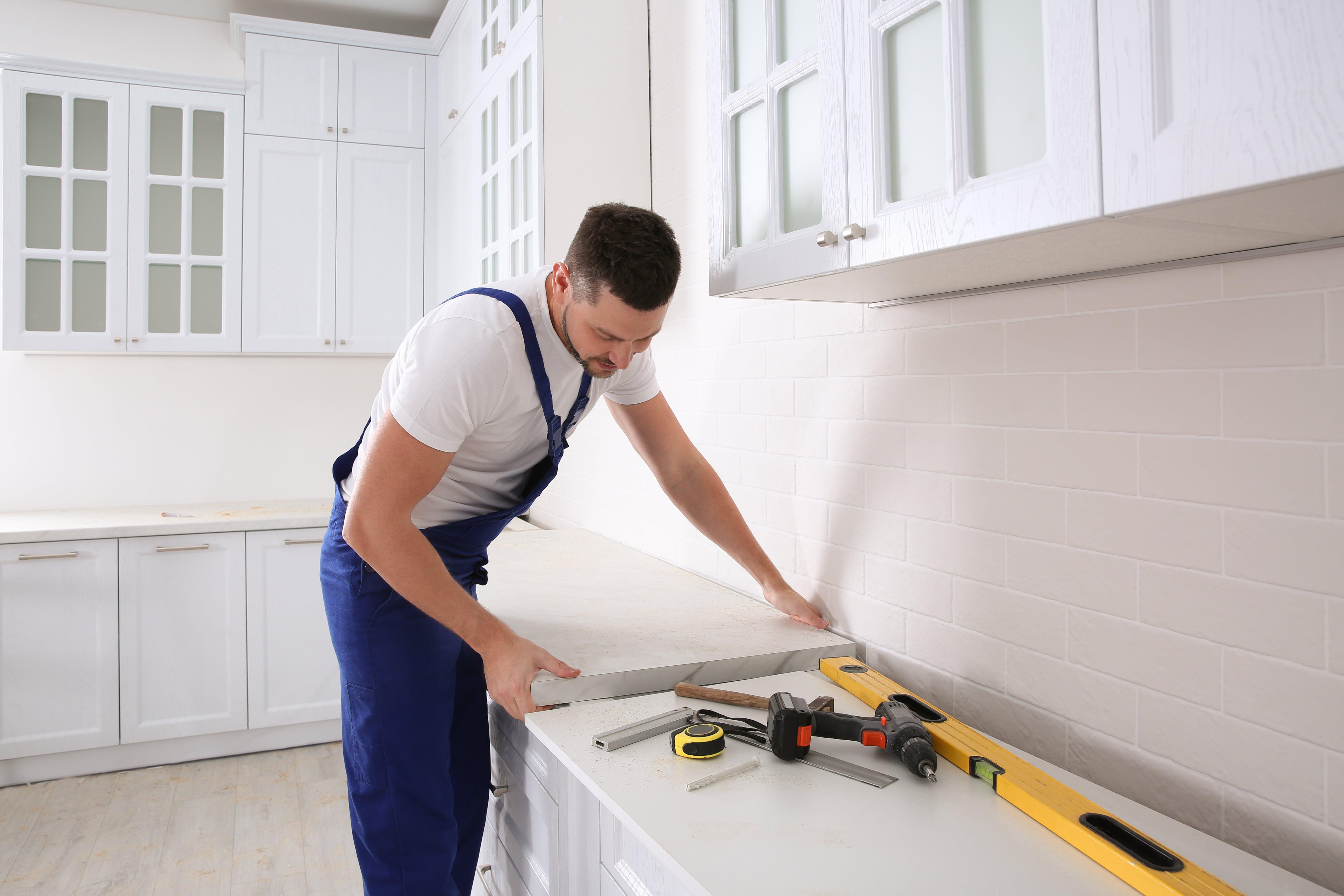 A man installing a kitchen counter as a home improvement project A man installing a kitchen counter as a home improvement project