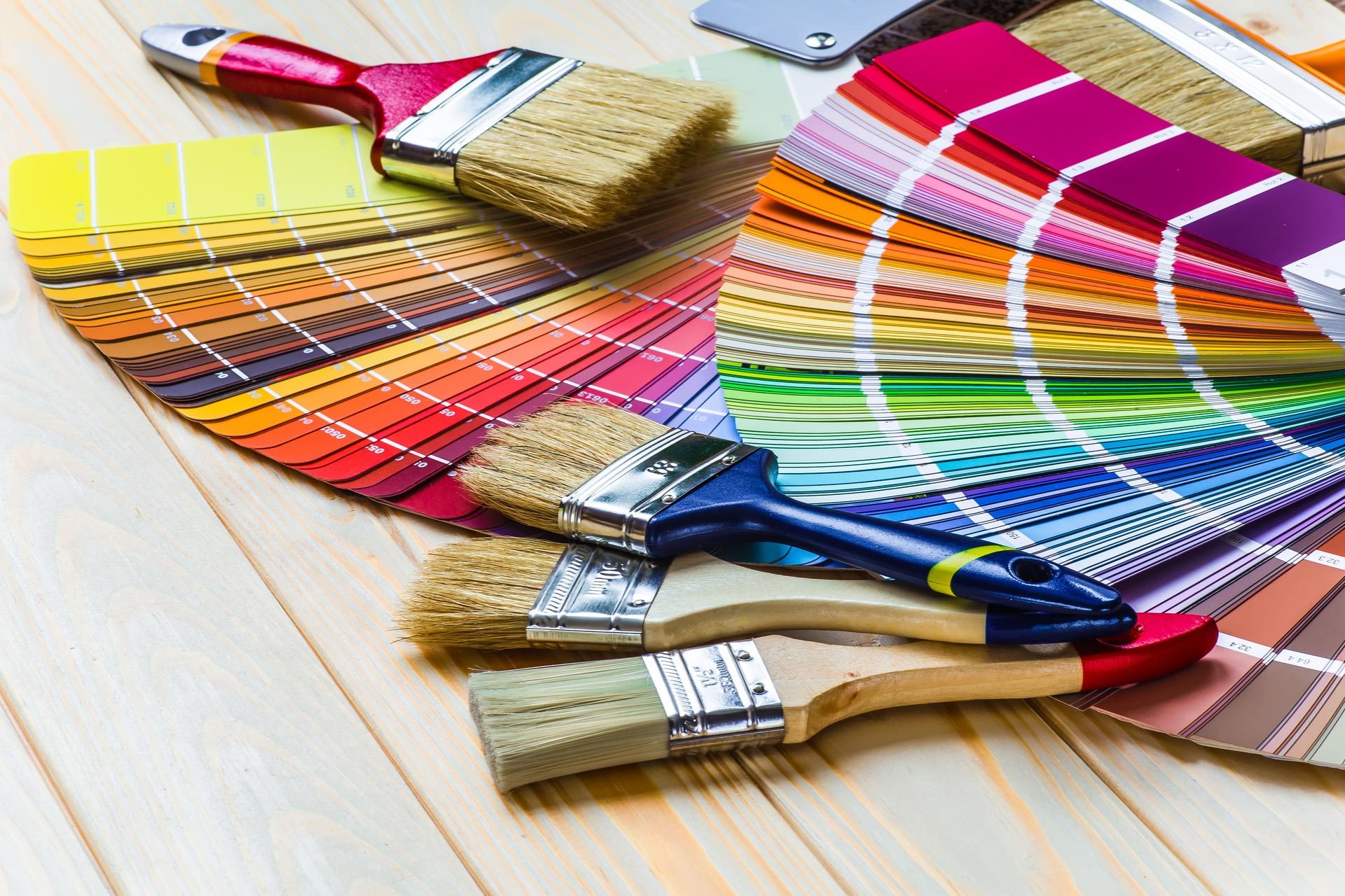 Layers of paint swatches and clean paintbrushes on a wood surface