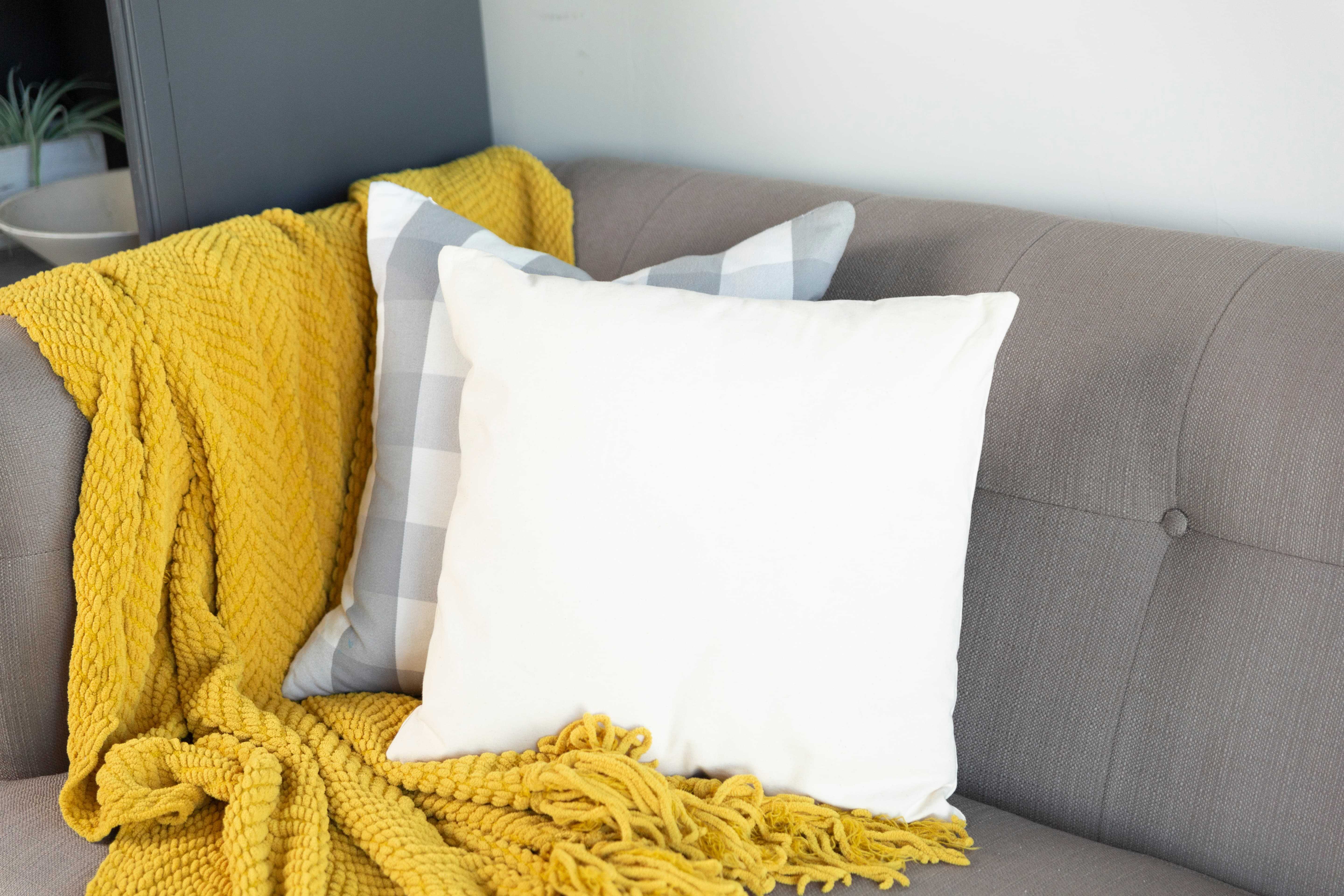 white pillow and yellow blanket on a gray couch