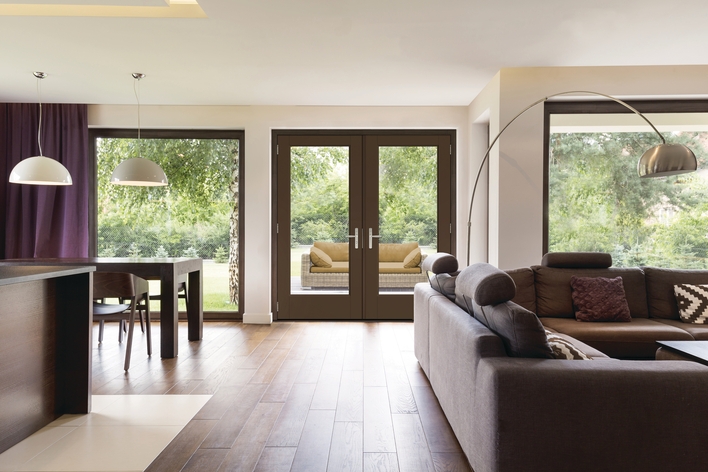 An open living space with wood accents and large windows and doors to a backyard patio.