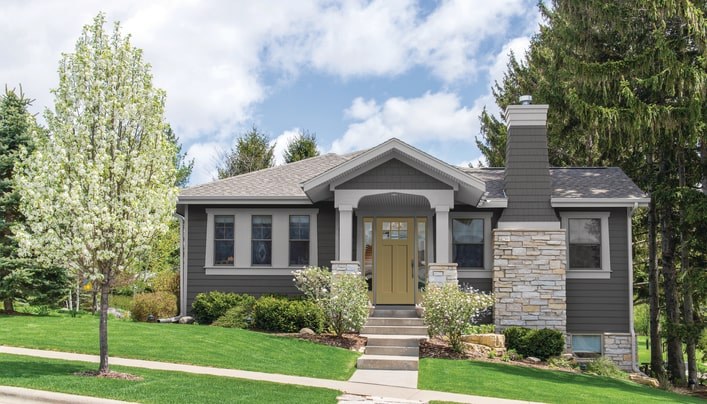 A tidy home exterior with gray siding and a yellow fiberglass front door.