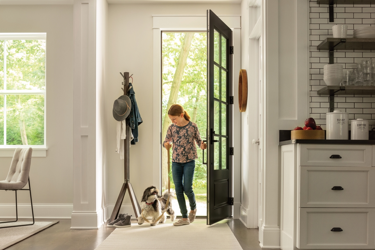 Girl entering front door of home with dog