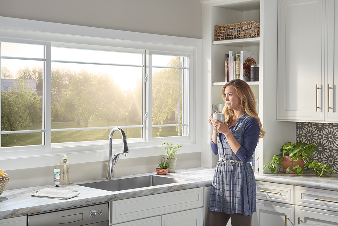 Woman enjoys morning sun from her kitchen window Woman enjoys morning sun from her kitchen window