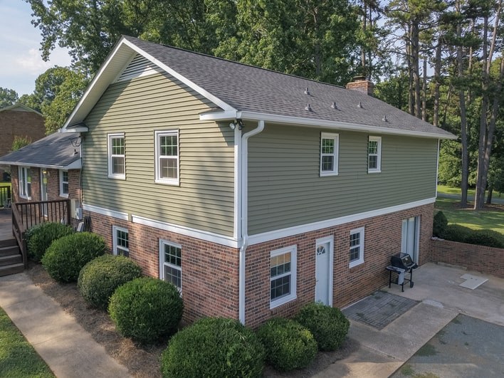 A house with a combination of vinyl siding and brick, both contrasted against white window frames and trim