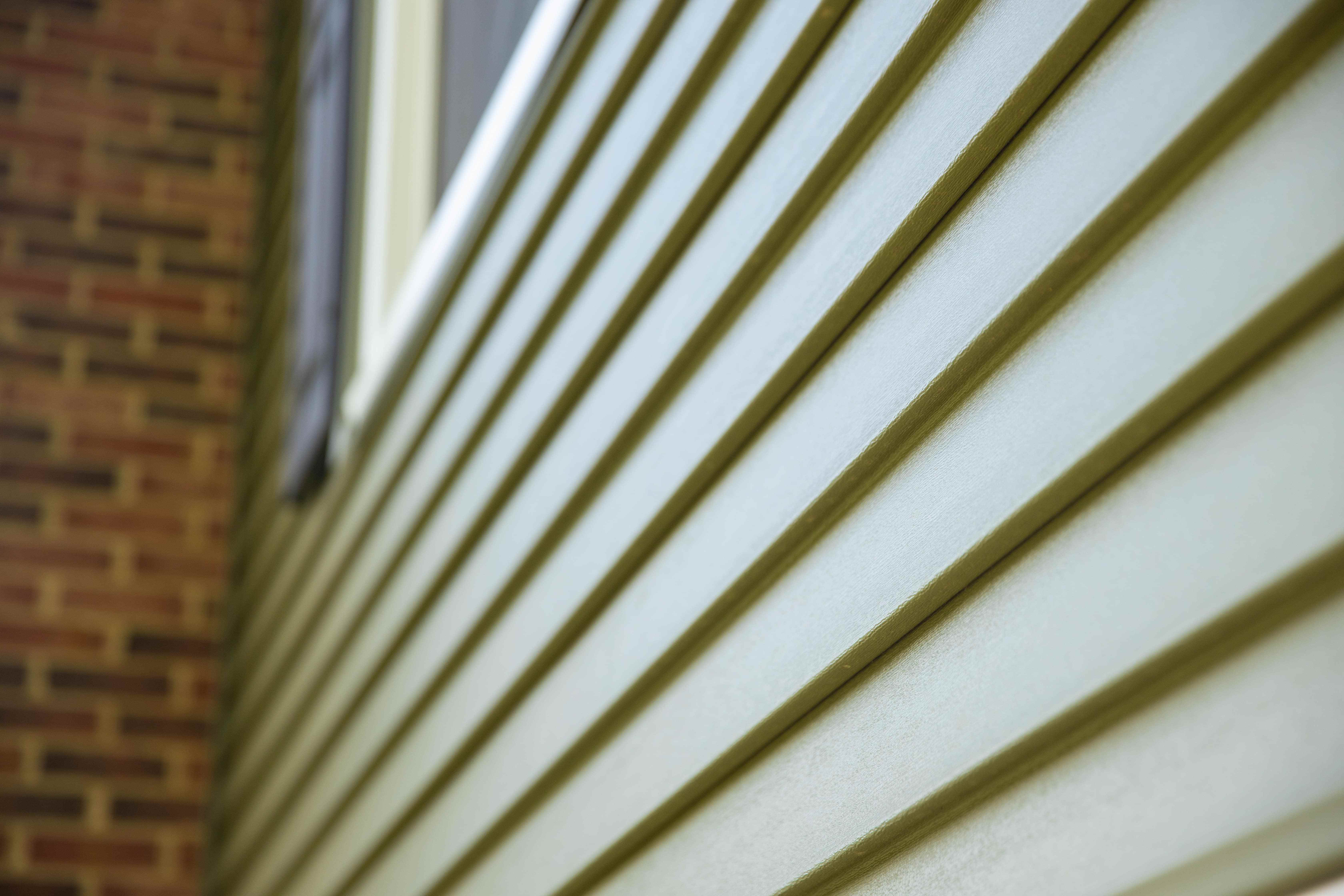 Closeup of clean vinyl siding on a house with a brick chimney