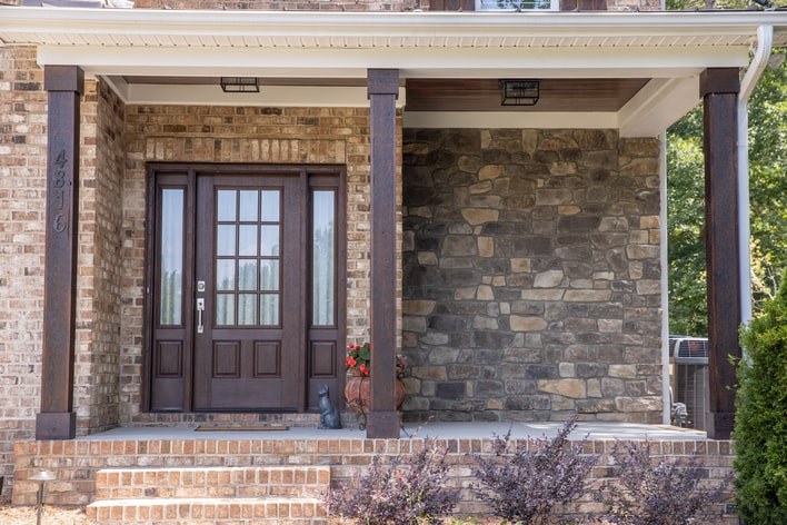 A brick house with a dark woodgrain front door and stone veneer added for curb appeal