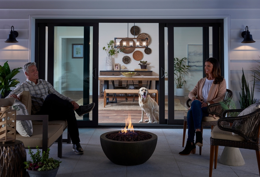 Couple enjoying a fire bowl in front of open sliding glass patio doors