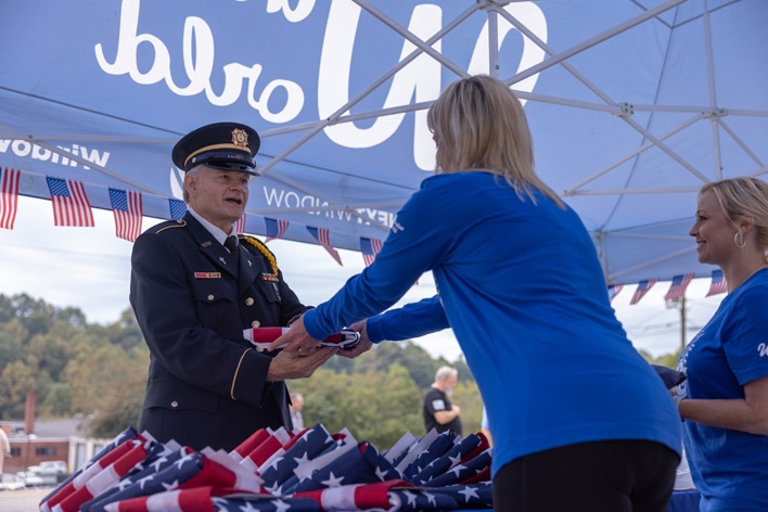 A member of the VFW exchanges an old American flag for a new one during Window World Old Glory Day