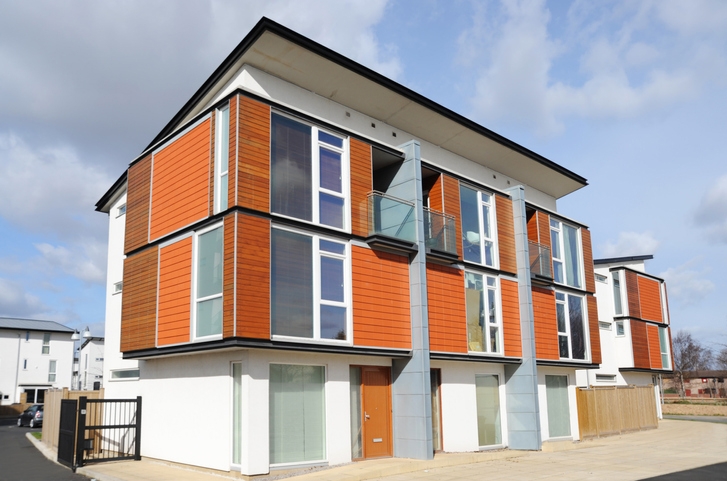 Modern architectural style house with a shed roof and wood planking details alongside large windows.