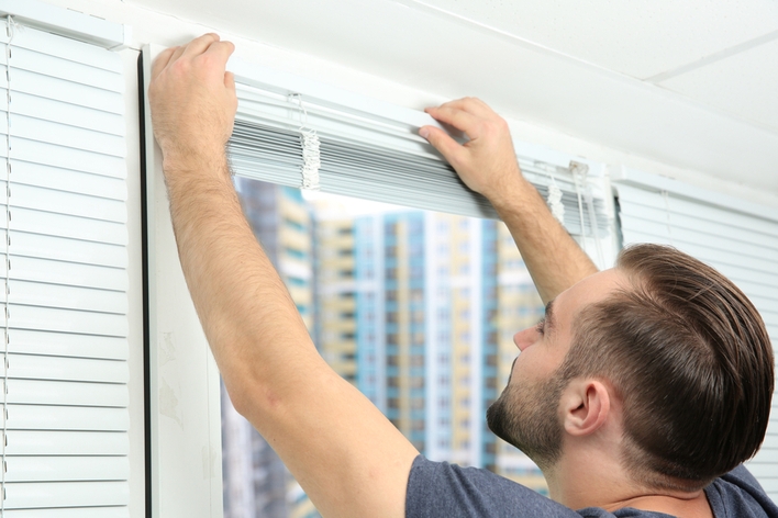 Man removing blinds before window installation