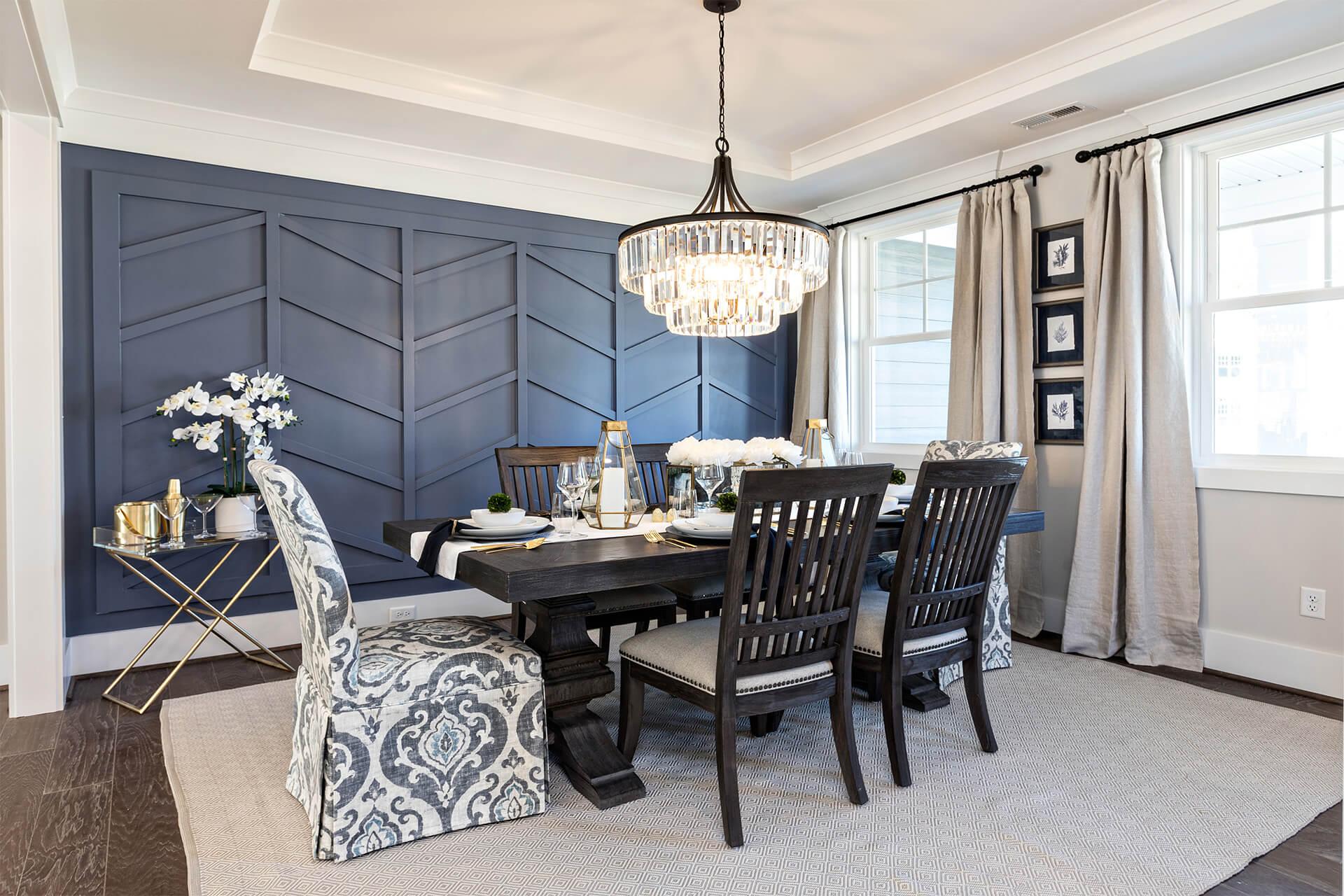 Luxurious looking home dining room with black chairs and a blue accent wall