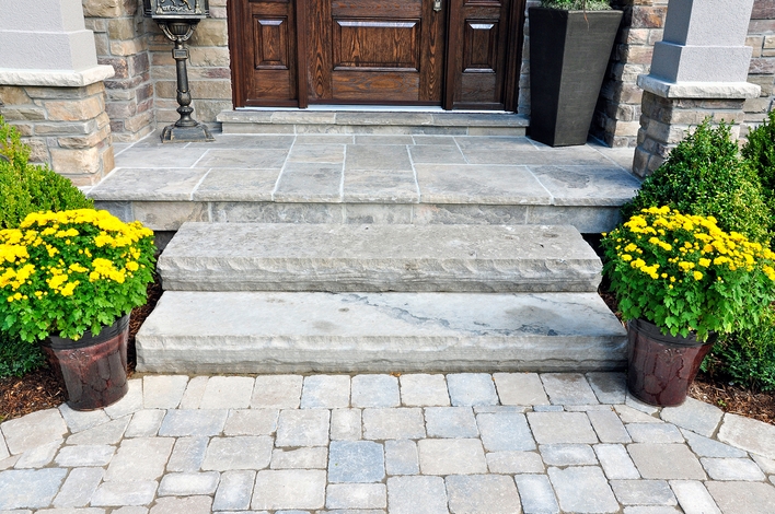A stone walkway to a front entrance, flanked with summer flowers