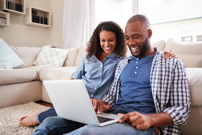 Happy couple looking at laptop in living room