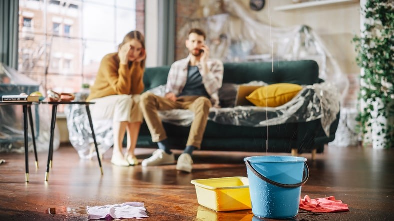 A bucket catching leaky water from the ceiling of a home