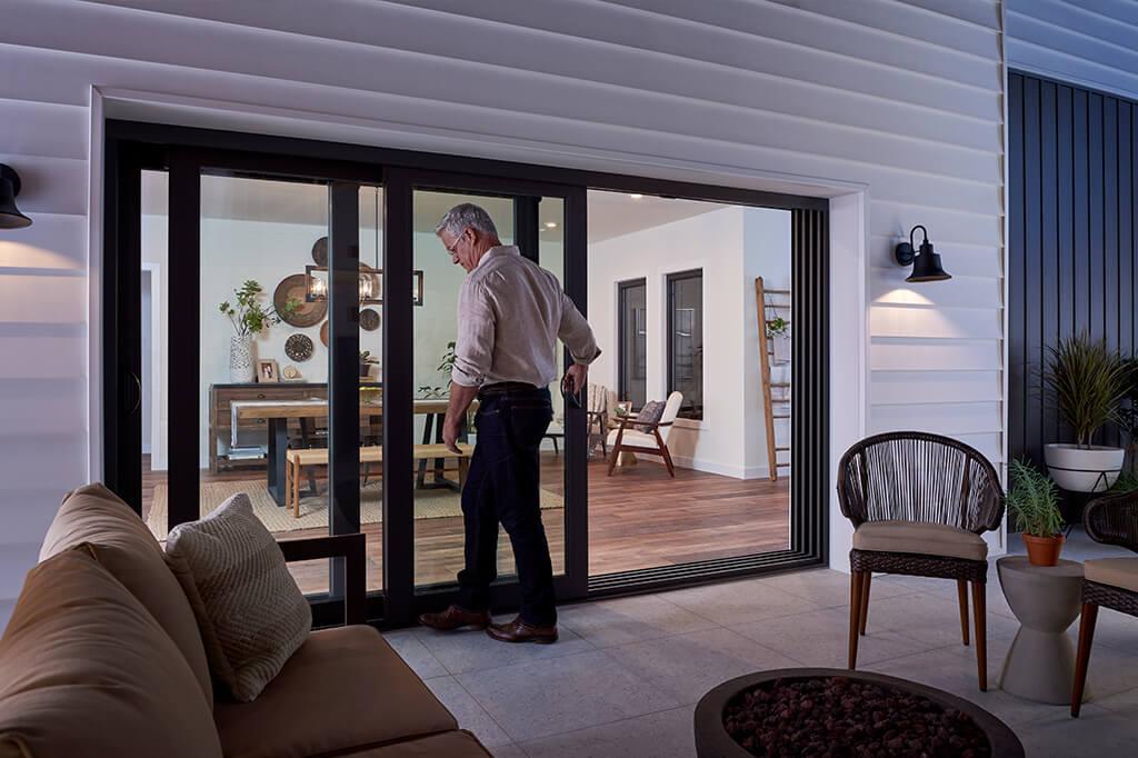 Man closing multi-panel sliding patio door