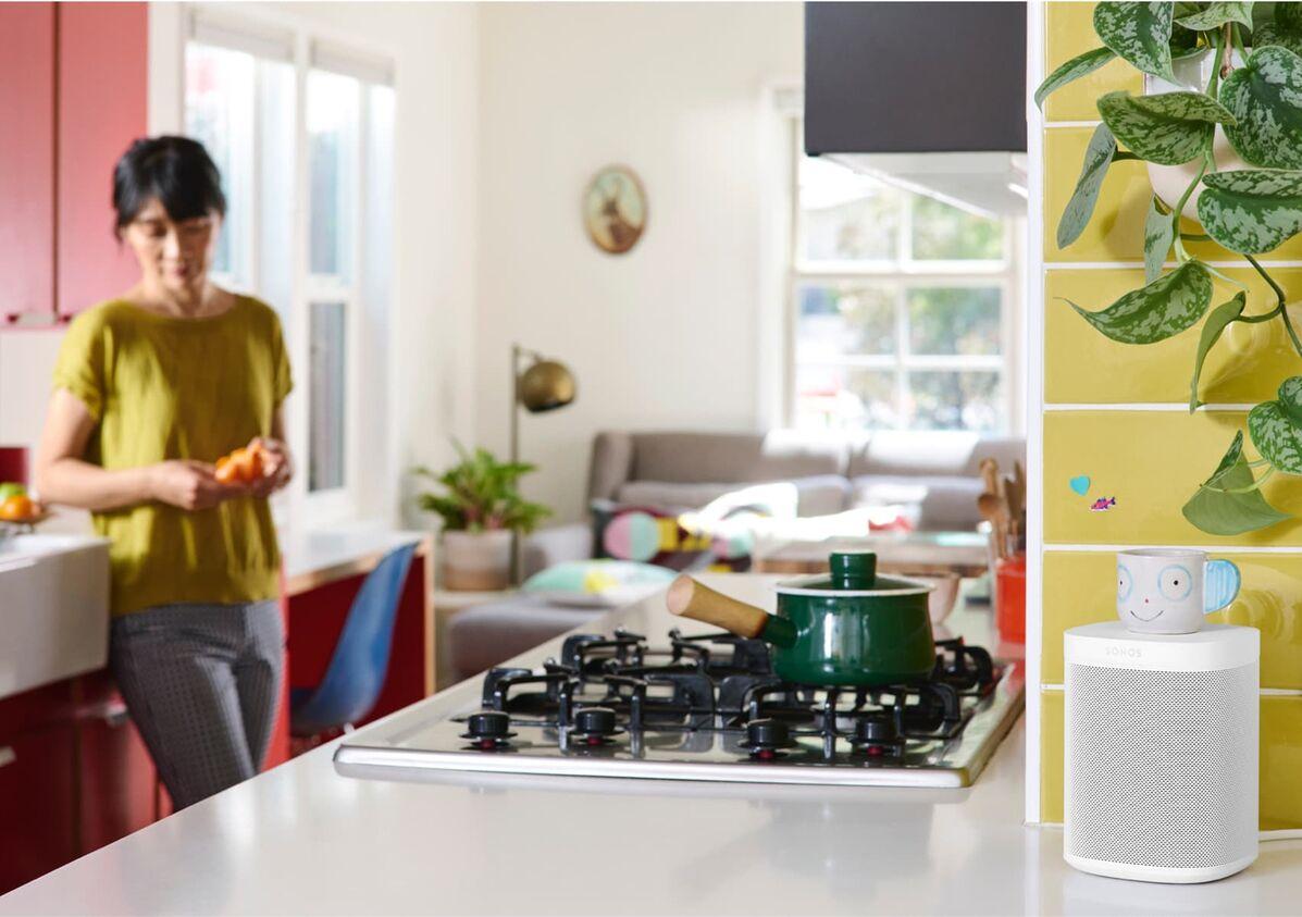 Woman in kitchen with smart speaker in foreground