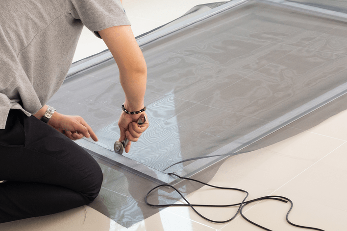 A person inserting the spline of a window screen replacement