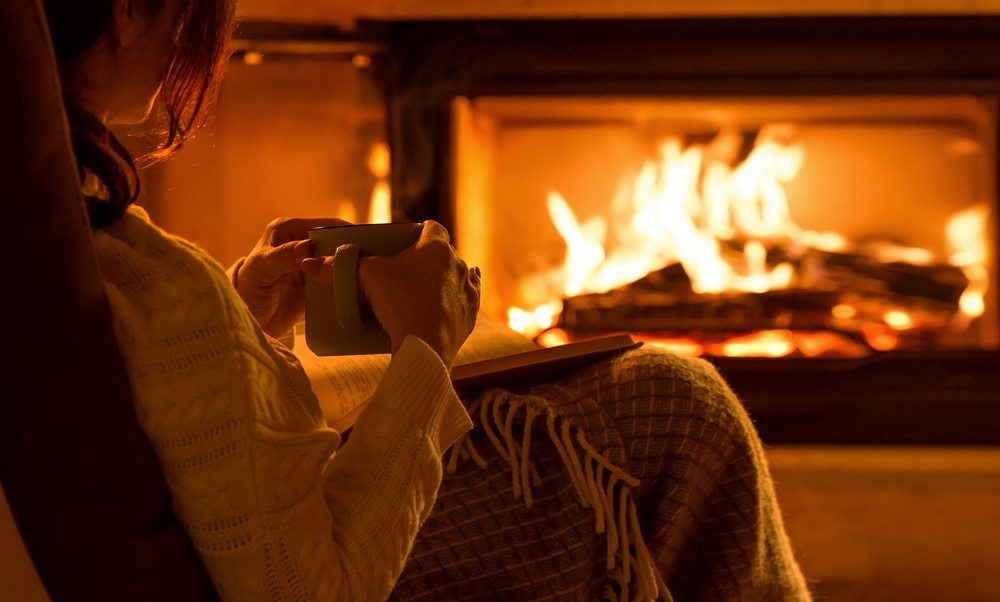 Woman sitting by fire with coffee