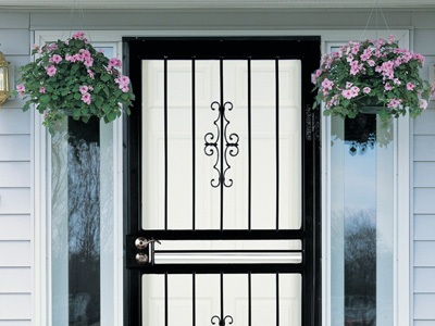 A storm door with black iron bars mounted on the front of a white entryway door.